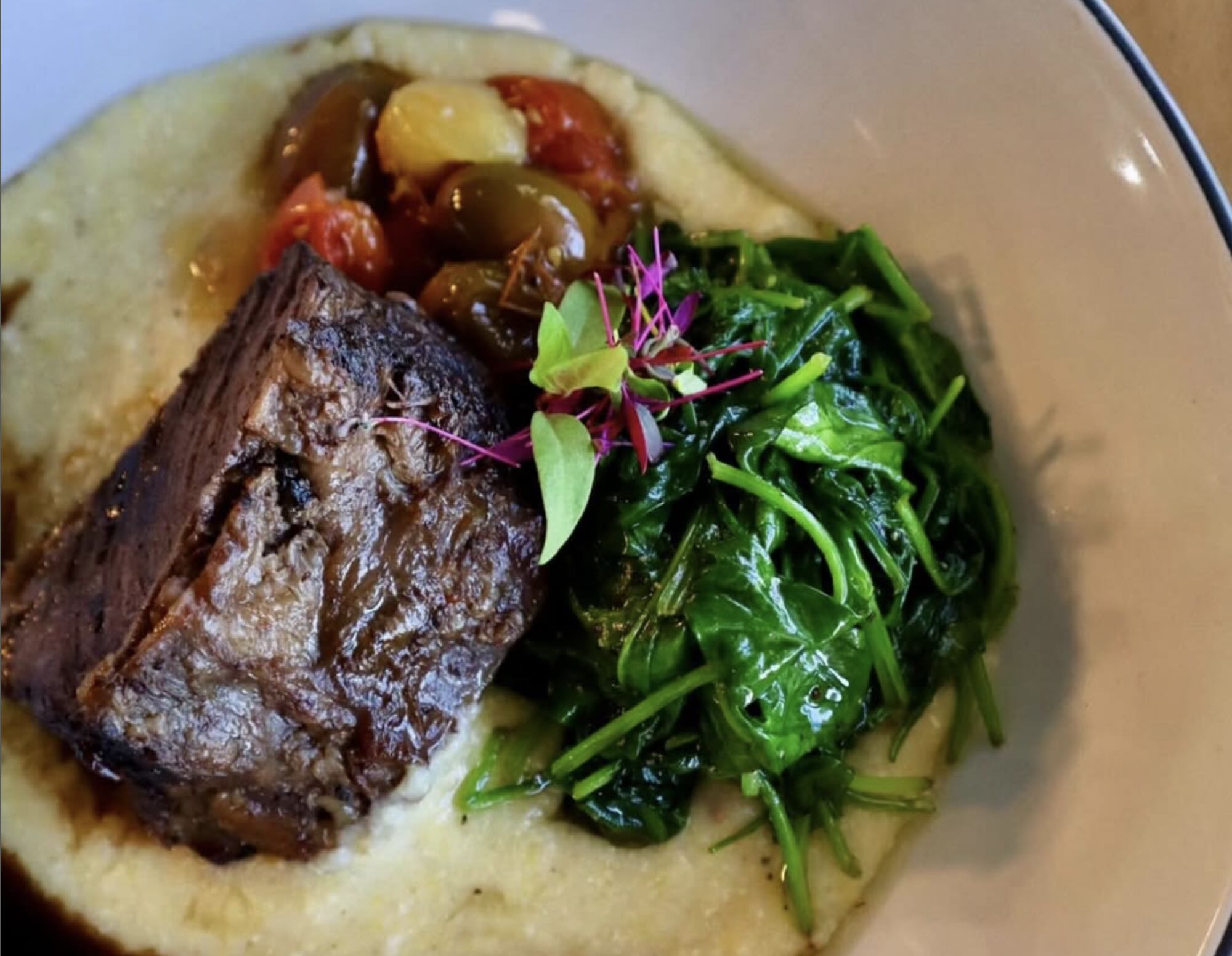 Shepherd with a flock of sheep in a green, hilly landscape.